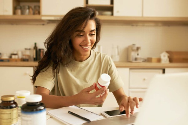 Young cute female posing indoor looking at thyroid supplements